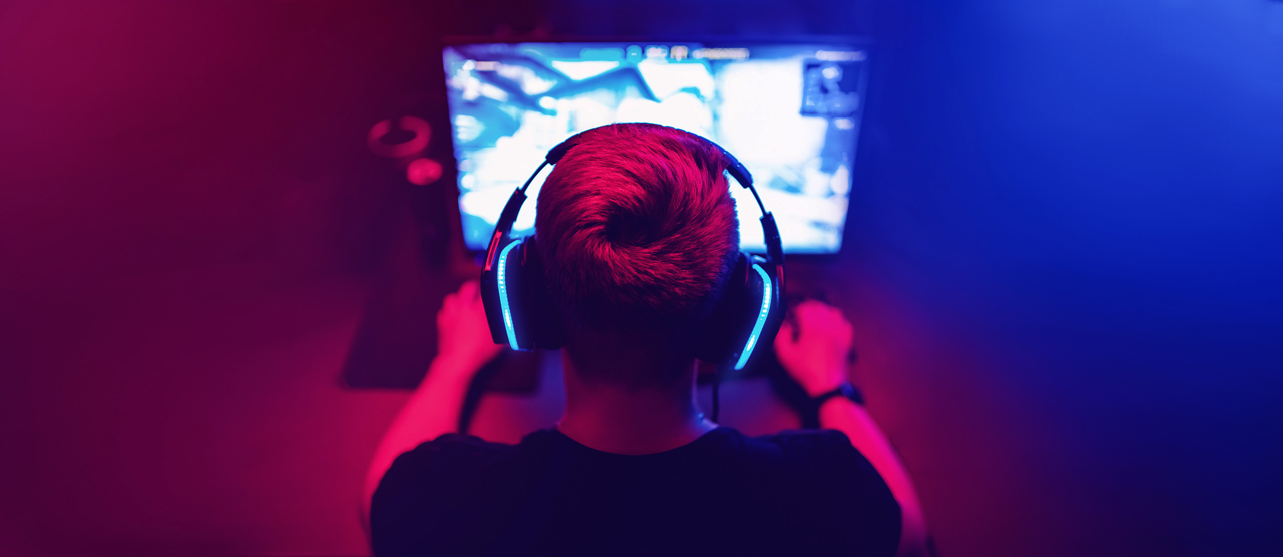 Gamer mit Headset, der vor seinem Computer sitzt und eSports spielt.